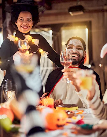 A lively dinner party where friends toast with champagne and share laughs under warm lights.